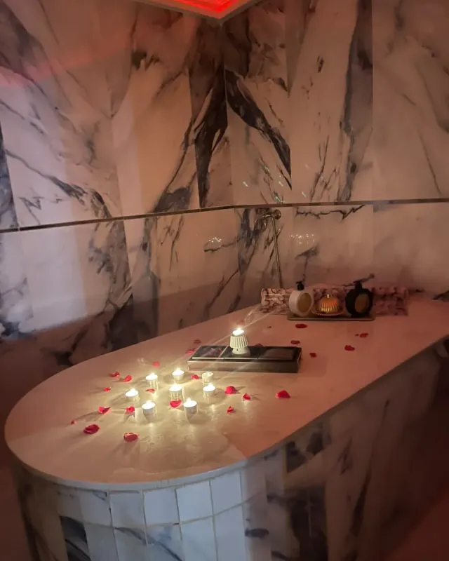 Table de hammam en marbre éclairée de bougies et parsemée de pétales de rose chez Arko Prestige Spa