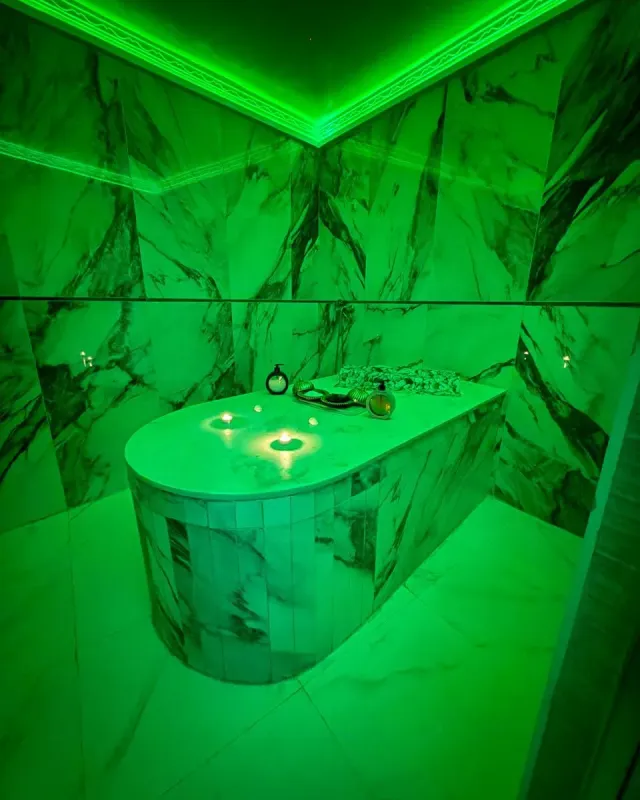 Table de hammam en marbre sous une lumière d’ambiance chez Arko Prestige Spa