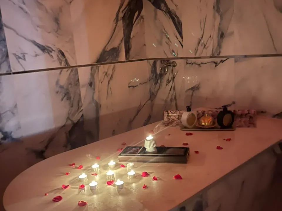 Table de hammam en marbre éclairée de bougies et parsemée de pétales de rose chez Arko Prestige Spa à Bourgogne, Casablanca