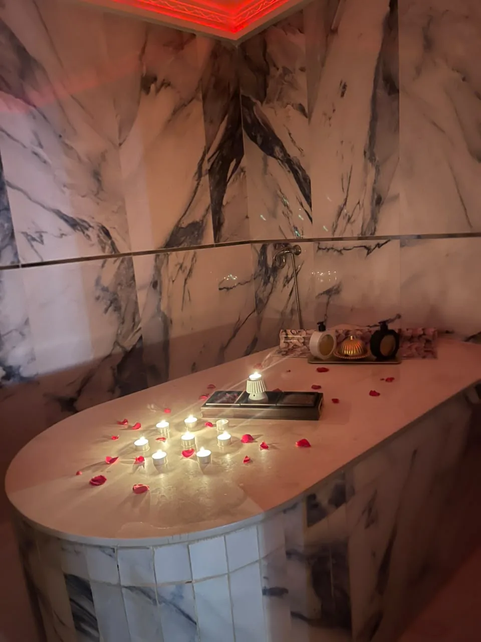Candlelit marble hammam table scattered with rose petals at Arko Prestige Spa in Bourgogne, Casablanca